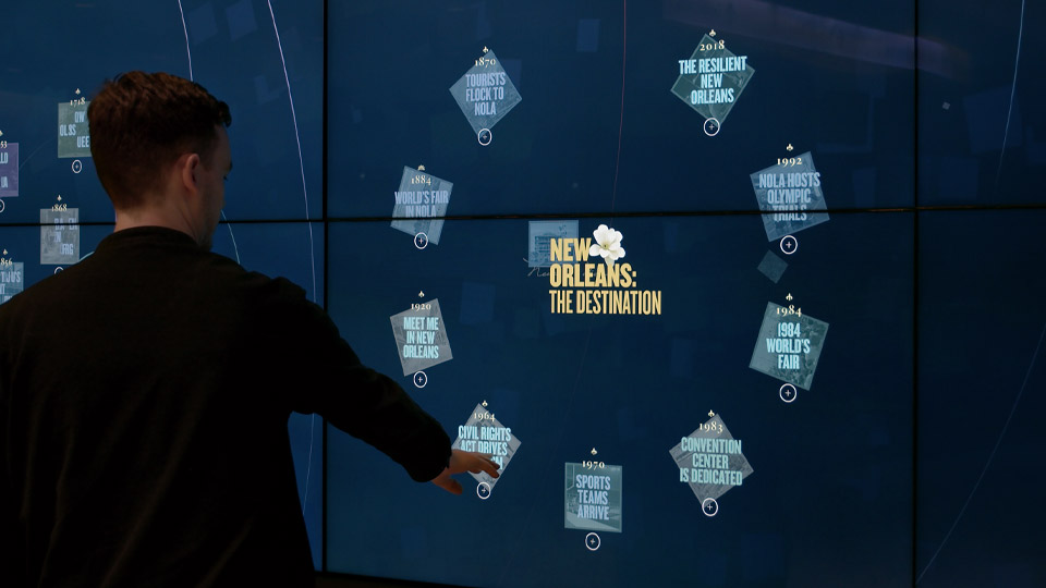 Interactive media wall in the lobby Visitor pointing at the interactive media wall in the convention center lobby