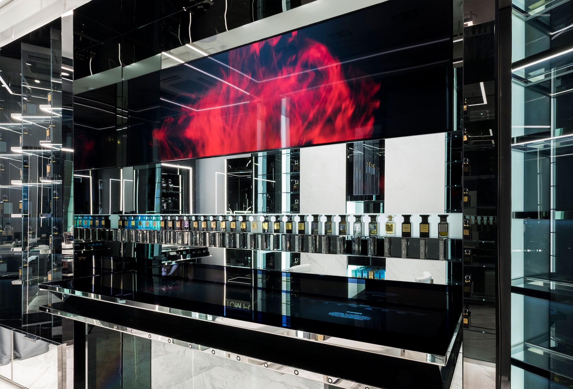 Mirrored fragrance counter with a red ink bloom playing on the screen